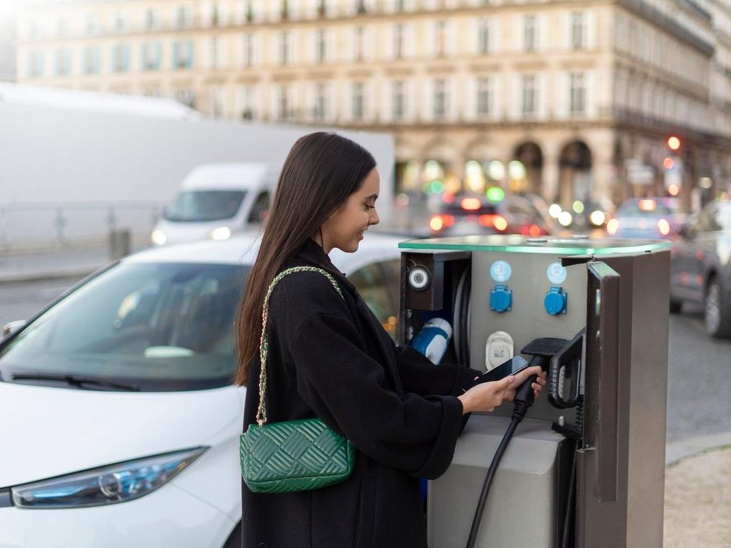 A driver starting a charging session from her phone at a public street charge point